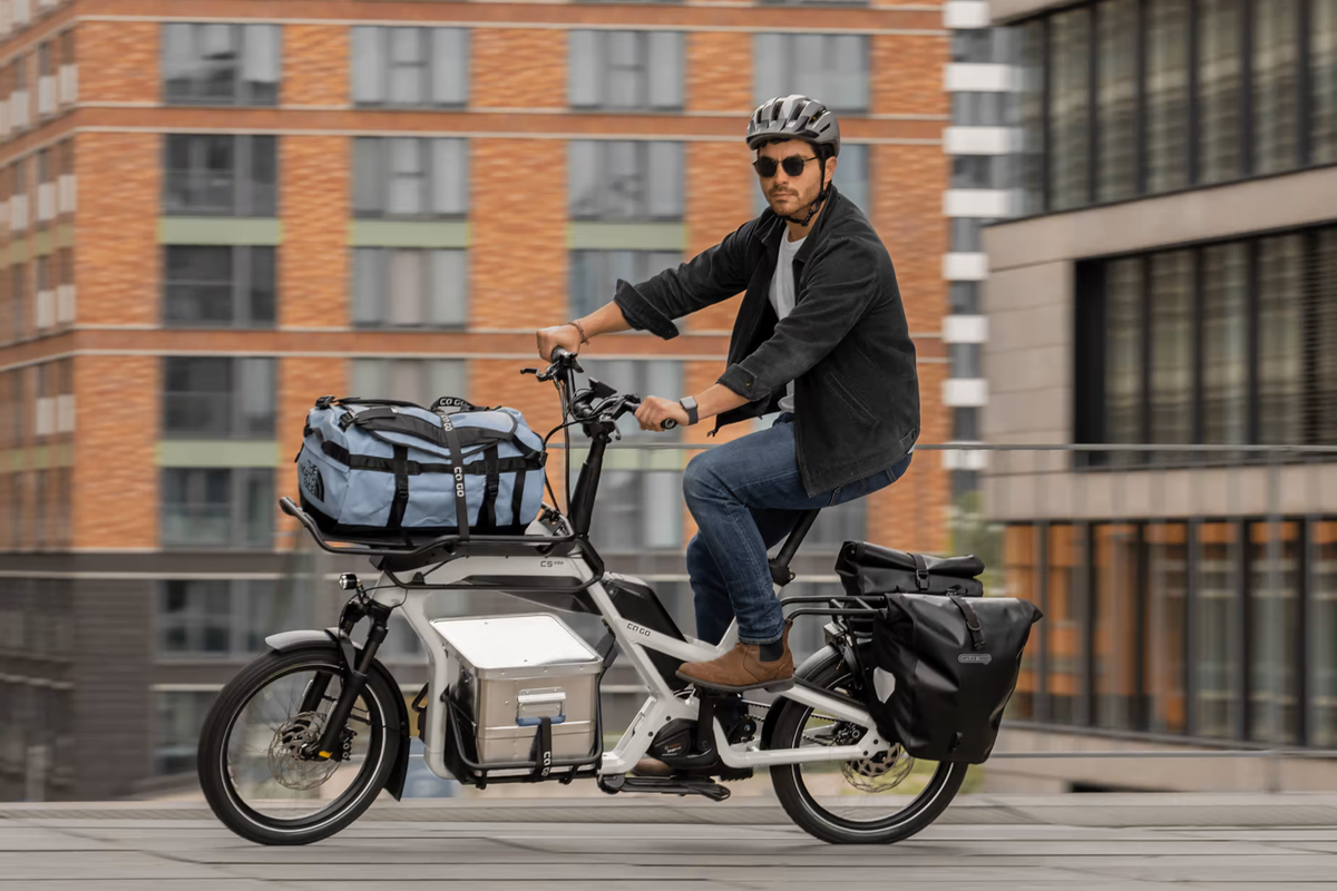 CaGo Eine beladenes CaGo Lastenrad auf der Straße, gefahren von einem Mann.